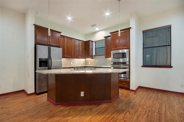 a kitchen with kitchen island granite countertop wooden floors and stainless steel appliances