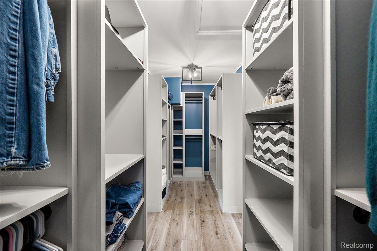 5035 Hidden Ridge Road Metamora, MI 48455 - Photo 22 of 62 Walk-through closet featuring extensive built-in shelving, hanging rods, and wood-finish flooring