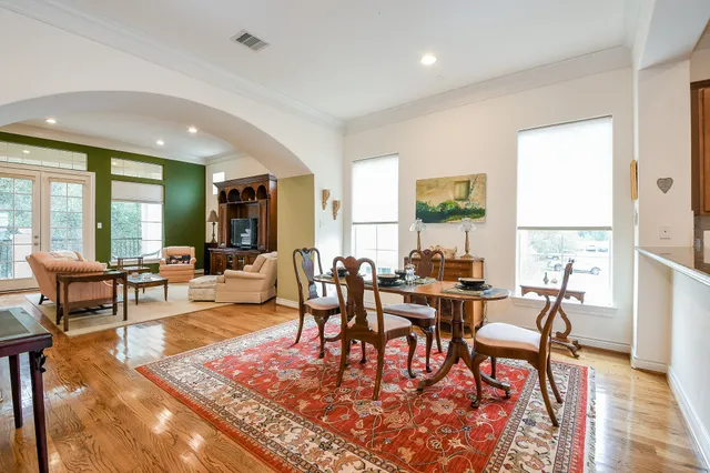a living room with furniture two large window and wooden floor