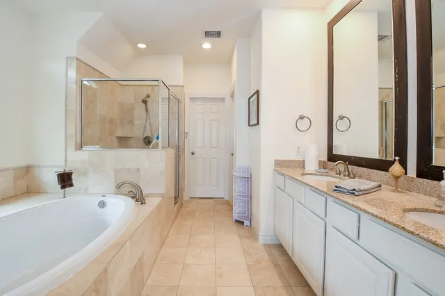 a spacious bathroom with a tub sink and mirror