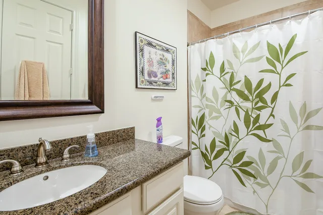 a bathroom with a granite countertop sink a toilet and a mirror