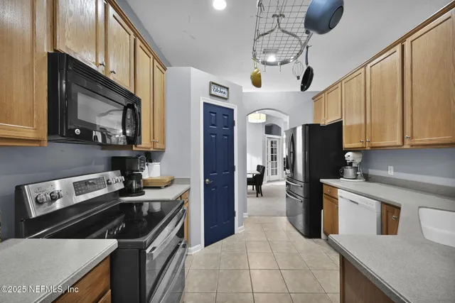 a kitchen with stainless steel appliances granite countertop a sink a stove top oven a refrigerator cabinets and a dining table with wooden floor