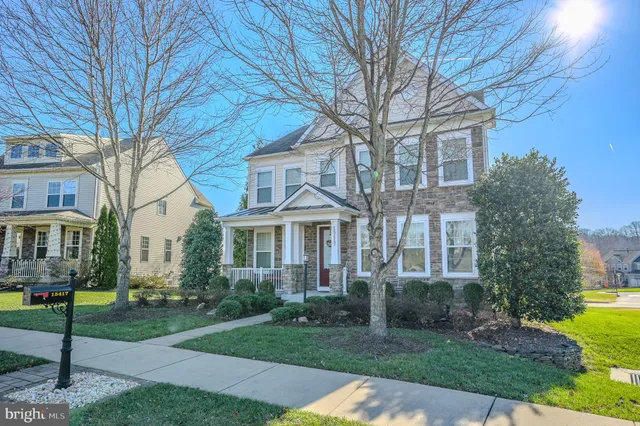 a view of a yard in front of a brick house with a large tree
