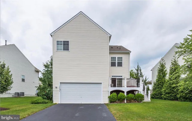 a view of a yard in front of a house with plants and large tree