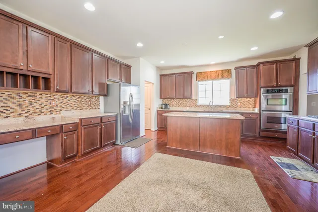 a kitchen with stainless steel appliances kitchen island granite countertop a stove refrigerator and cabinets