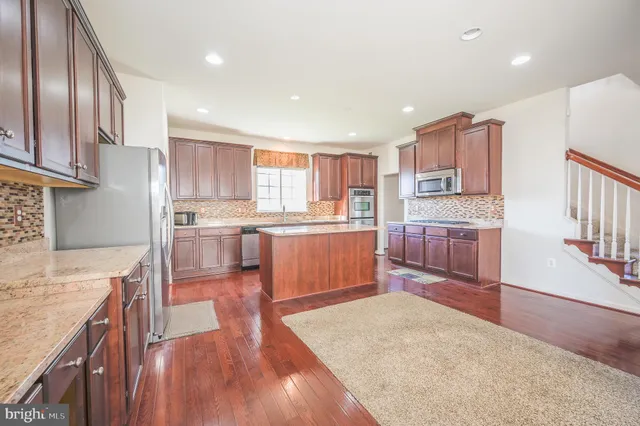 a kitchen with stainless steel appliances granite countertop a refrigerator sink and wooden cabinets