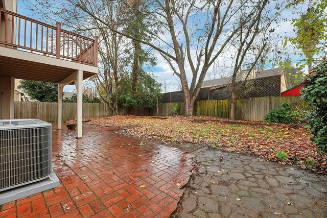 a backyard of a house with large trees and outdoor seating