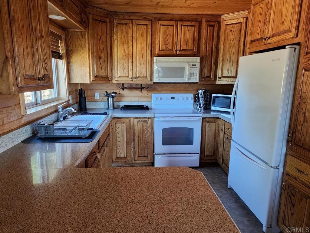 34675 Yuma Road Julian, CA 92036 - Photo 9 of 28 a kitchen with stainless steel appliances granite countertop a refrigerator a stove a sink dishwasher and wooden cabinets with wooden floor