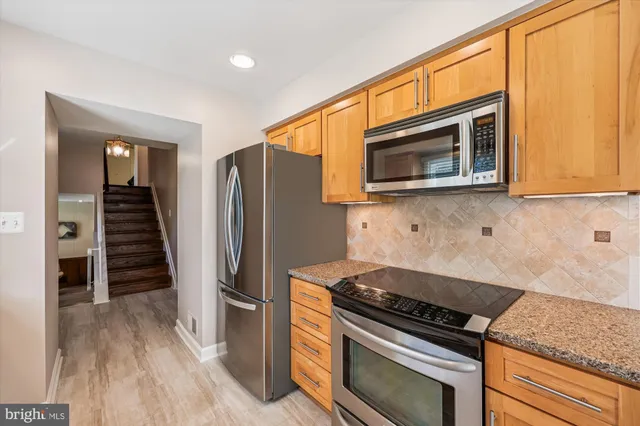 a kitchen with granite countertop a refrigerator and a stove top oven