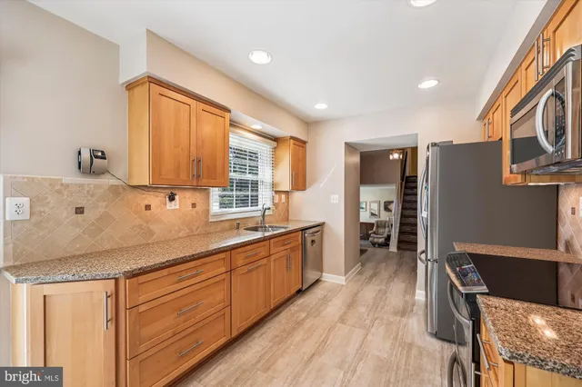 a large kitchen with stainless steel appliances granite countertop a lot of counter space and wooden floors