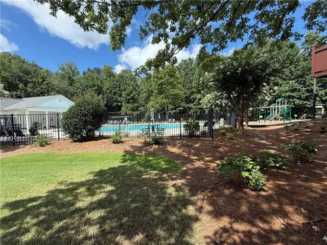 a view of pool with lawn chairs under an umbrella