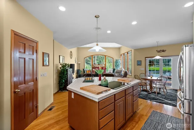 a view of a kitchen counter top space with stainless steel appliances granite countertop a stove and a wooden floors