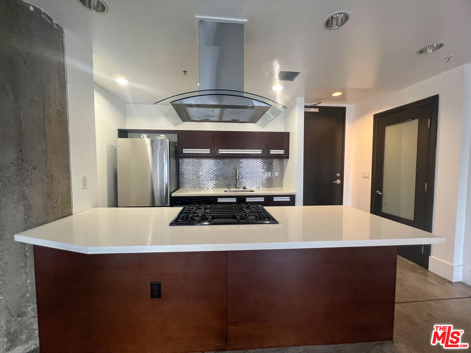 810 South Spring Street, Unit 801 Los Angeles, CA 90014 - Photo 2 of 21 a kitchen with kitchen island a sink a stove and white cabinets