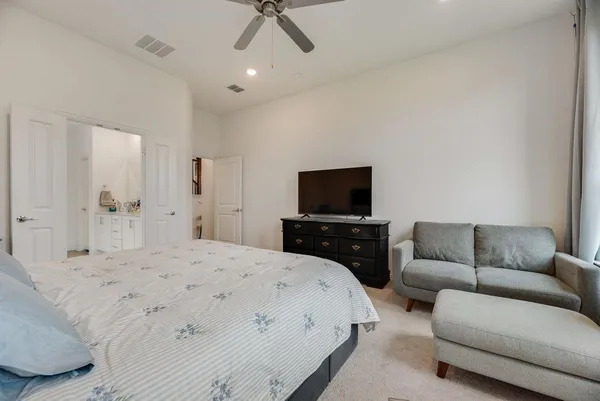 a bedroom with a bed a couch and a flat screen tv