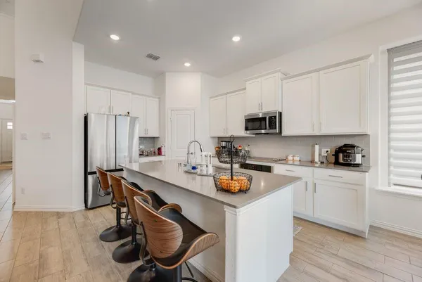 a kitchen with a sink a stove a refrigerator cabinets and a dining table