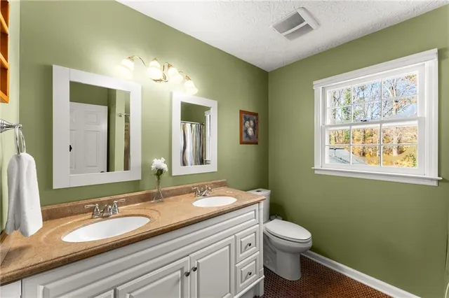 a bathroom with a granite countertop toilet sink and mirror