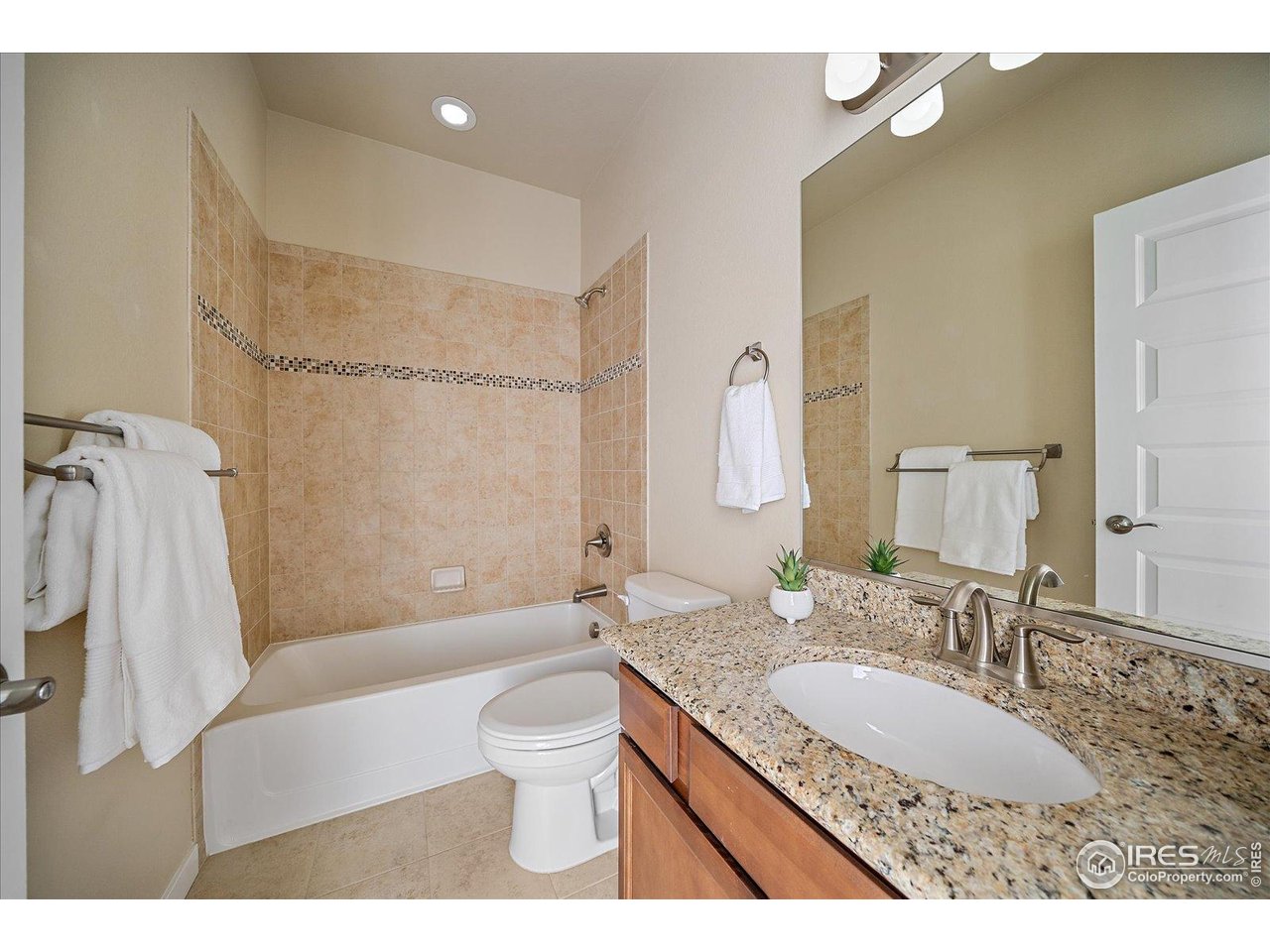 2321 Nicholson Street Berthoud, CO 80513 - Photo 14 of 22 a bathroom with a granite countertop sink a toilet a mirror a bathtub and shower