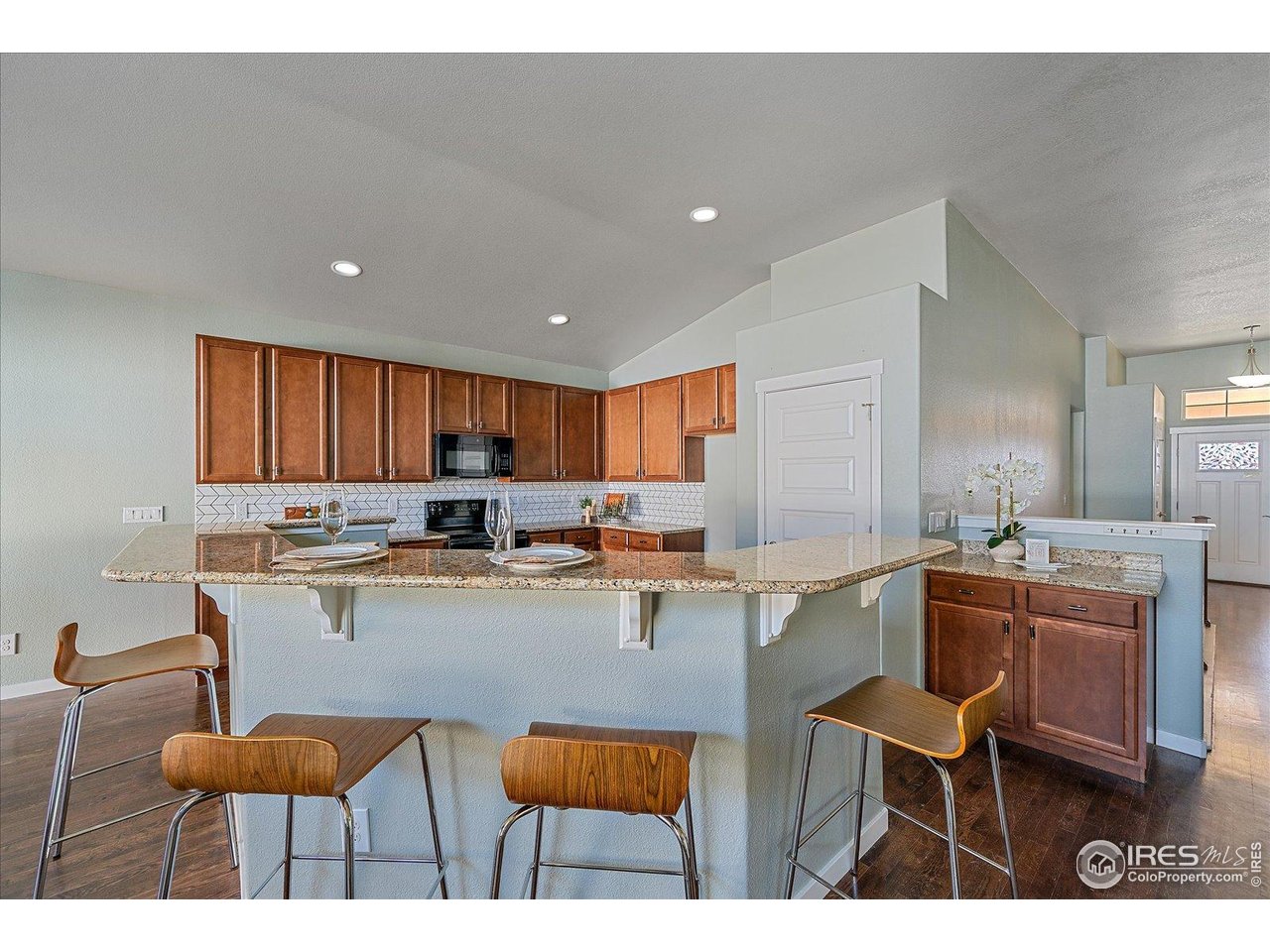 2321 Nicholson Street Berthoud, CO 80513 - Photo 8 of 22 a kitchen with stainless steel appliances kitchen island granite countertop a table chairs sink and cabinets