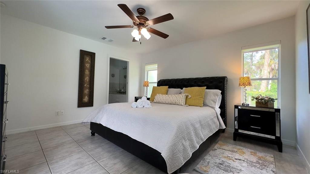 3440 15th Avenue Southwest Naples, FL 34117 - Photo 16 of 31 Tiled bedroom featuring multiple windows, connected bathroom, and ceiling fan