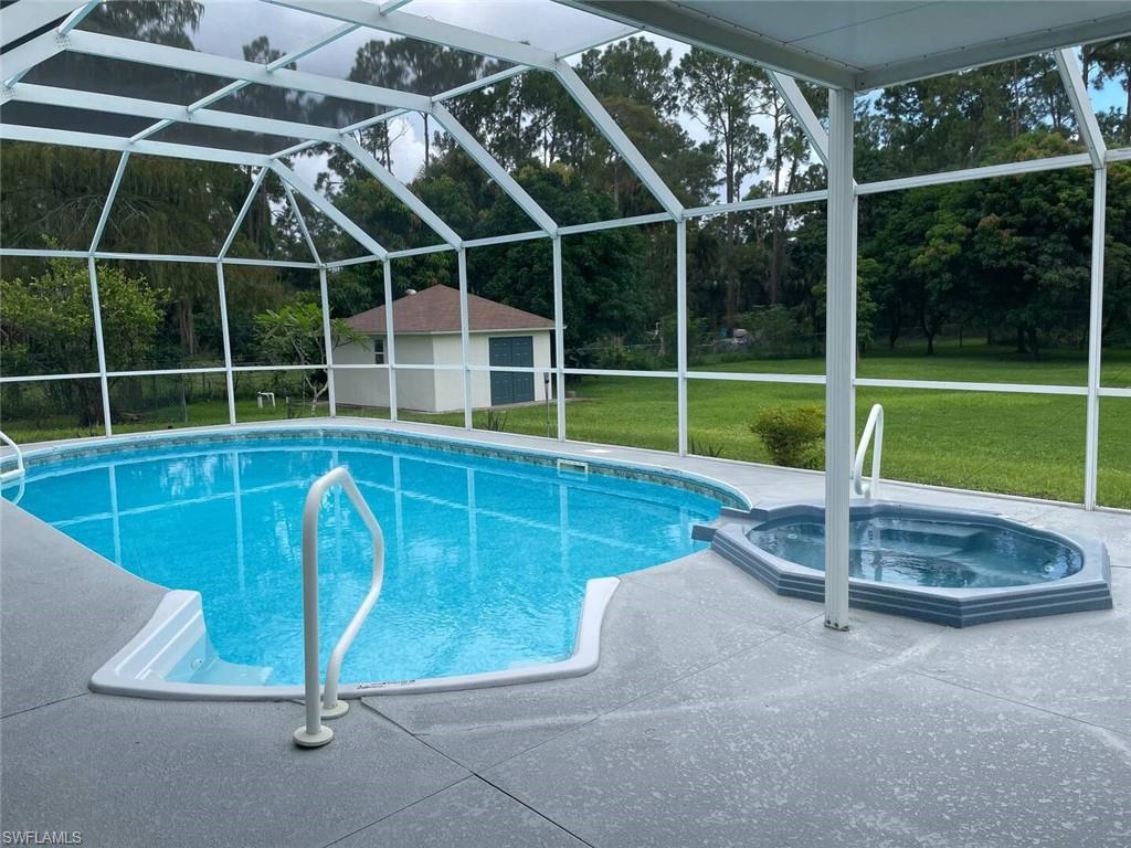 3440 15th Avenue Southwest Naples, FL 34117 - Photo 22 of 31 View of swimming pool featuring a lanai, an outbuilding, a lawn, and an in ground hot tub