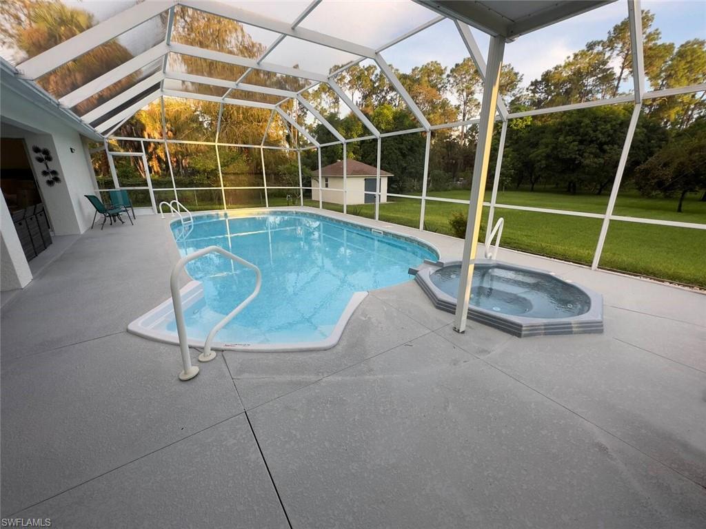 3440 15th Avenue Southwest Naples, FL 34117 - Photo 23 of 31 View of pool featuring a patio area, a yard, a lanai, an in ground hot tub, and a storage unit