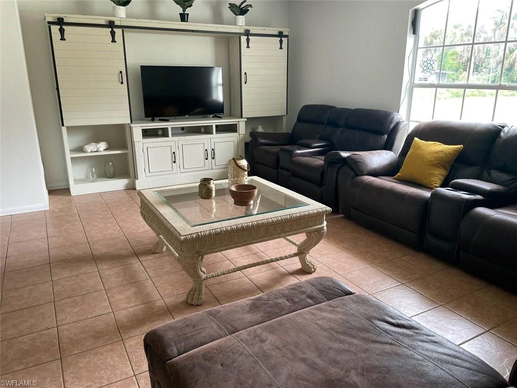 3440 15th Avenue Southwest Naples, FL 34117 - Photo 26 of 31 Living room featuring a barn door, light tile patterned floors, and built in features