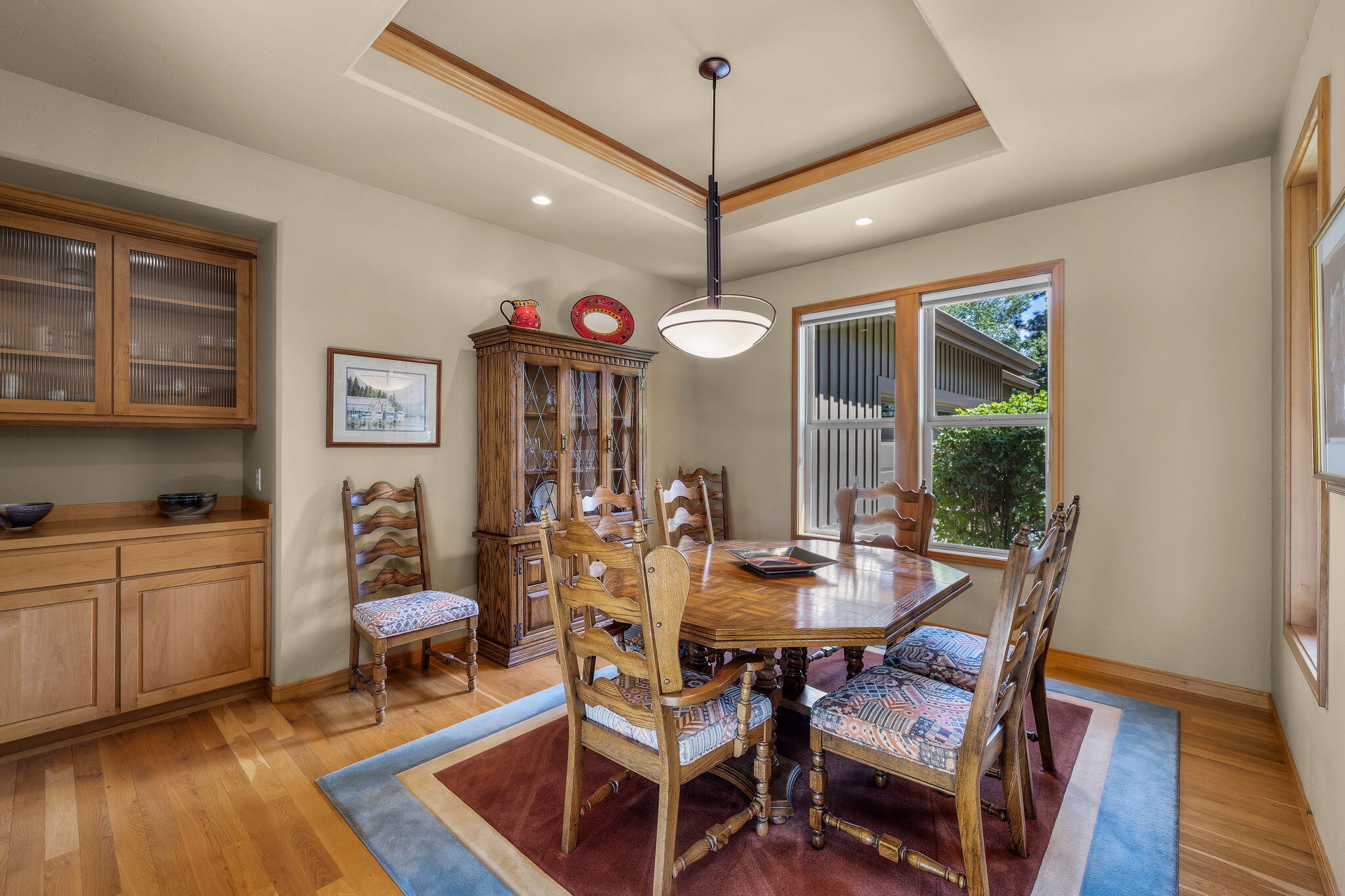 19574 Green Lakes Loop Bend, OR 97702 - Photo 16 of 41 A dedicated dining room with hardwood floors, tray ceiling detail, built-in cabinetry, and large windows overlooking the landscaped front setting.