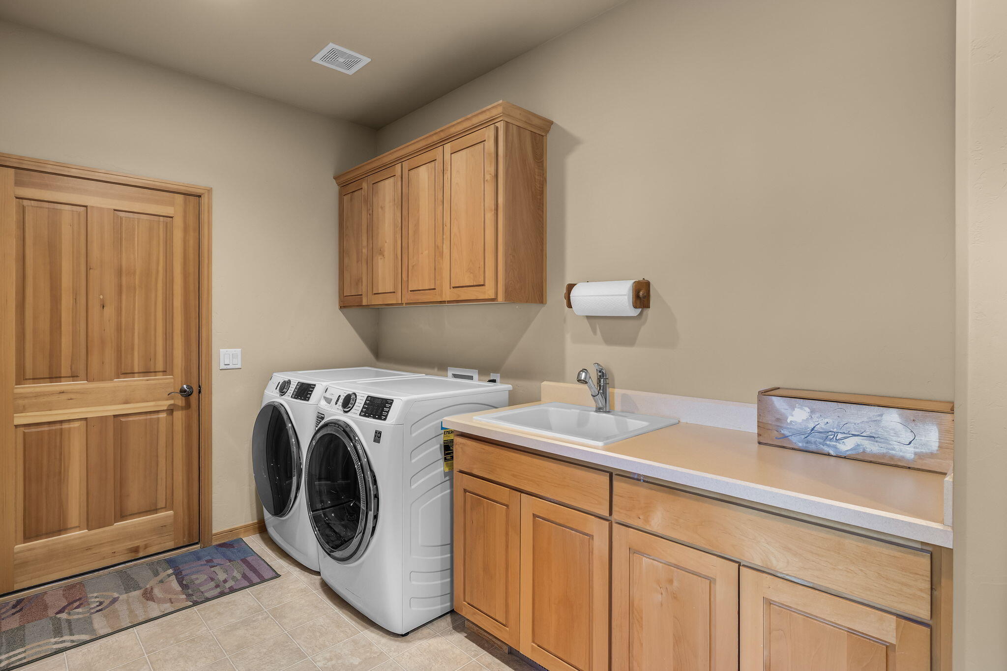 19574 Green Lakes Loop Bend, OR 97702 - Photo 30 of 41 Spacious laundry room with sink, cabinetry, folding counter, tile flooring, and direct access toward the garage area.