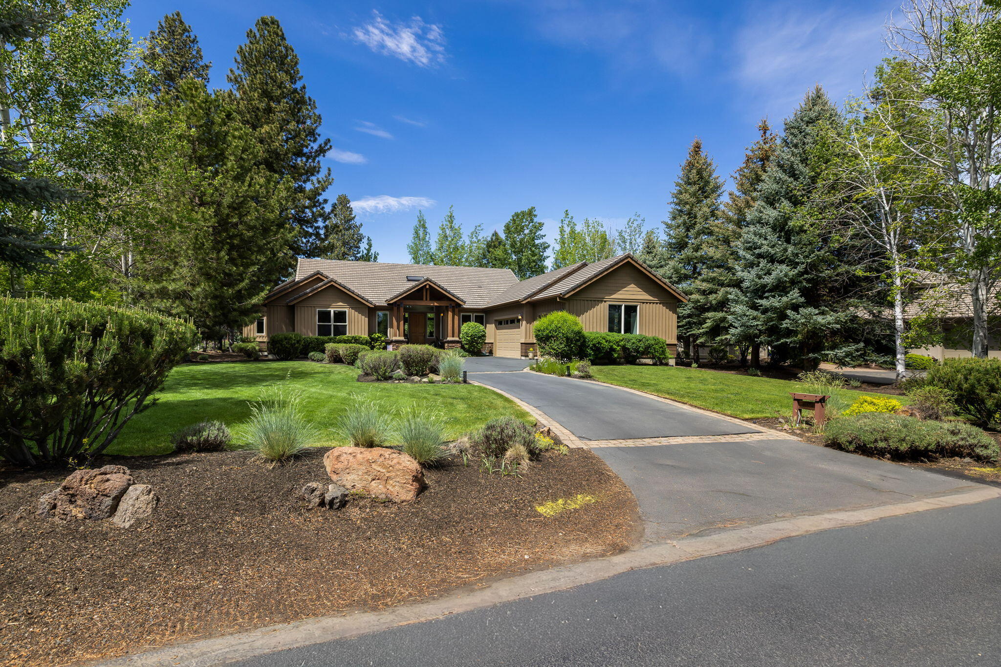 19574 Green Lakes Loop Bend, OR 97702 - Photo 3 of 41 A welcoming approach with manicured grounds, mature landscaping, and a generous driveway leading to the three-car garage.