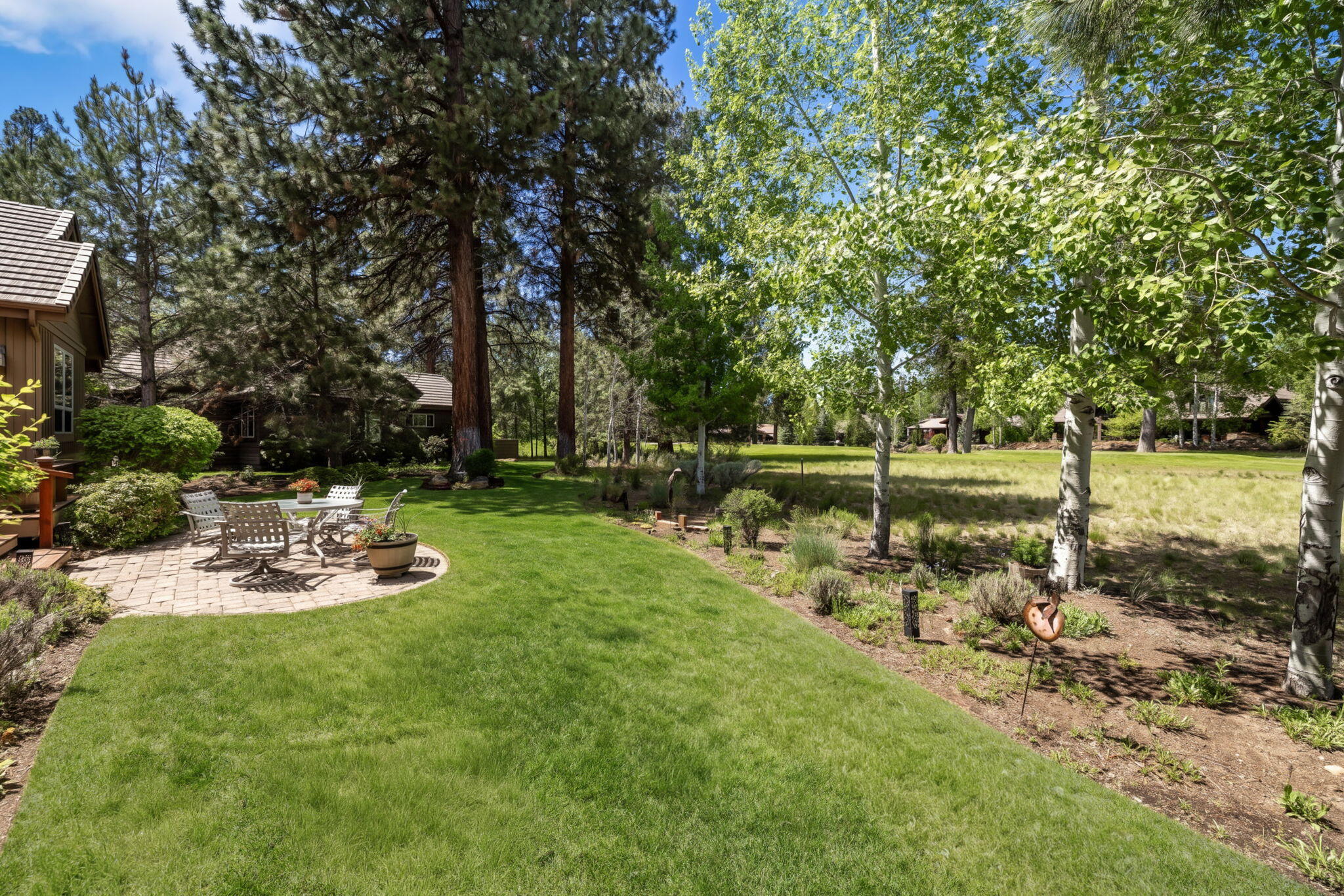 19574 Green Lakes Loop Bend, OR 97702 - Photo 36 of 41 The rear patio and lawn offer a peaceful setting framed by mature trees, native landscaping, and open views toward the 17th fairway.