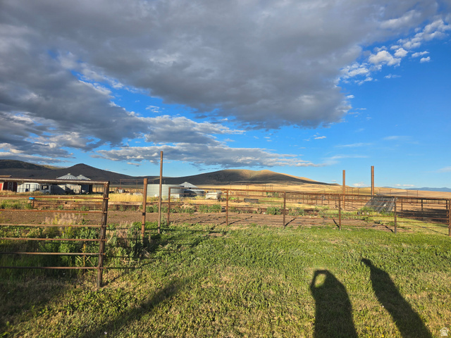 34200 Coulam Road Swan Lake, ID 83281 - Photo 22 of 24 Expansive property featuring verdant foreground, fencing, and distant structures, all set against a backdrop of rolling hills and open sky