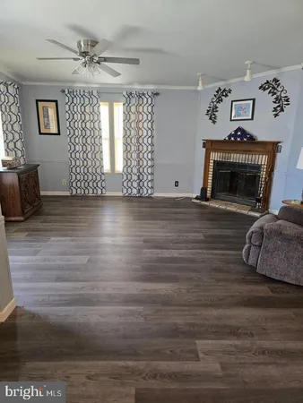a view of a livingroom with a fireplace a ceiling fan and windows