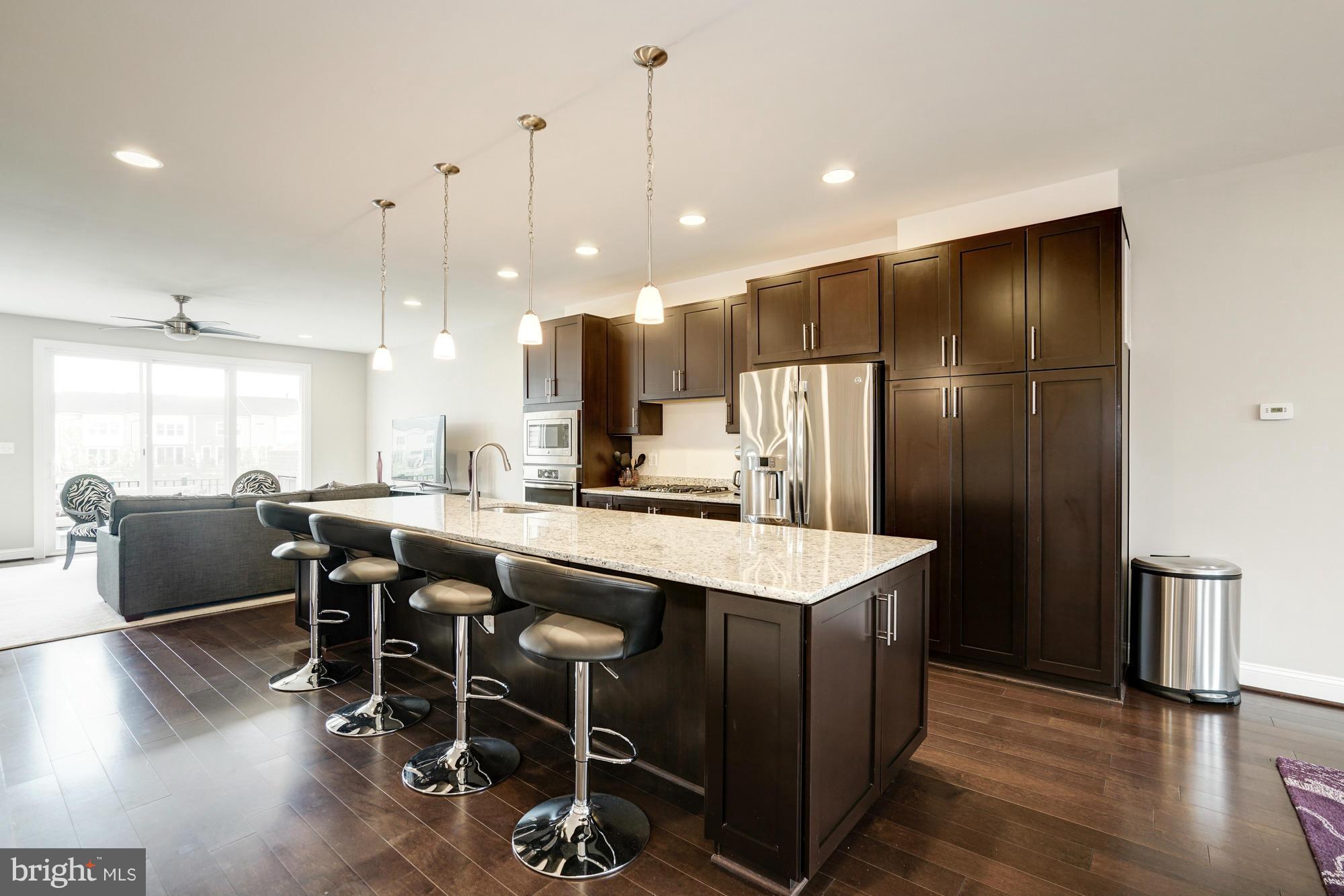 42277 Riggins Ridge Terrace Ashburn, VA 20148 - Photo 13 of 30 a kitchen with kitchen island a dining table chairs stainless steel appliances and cabinets