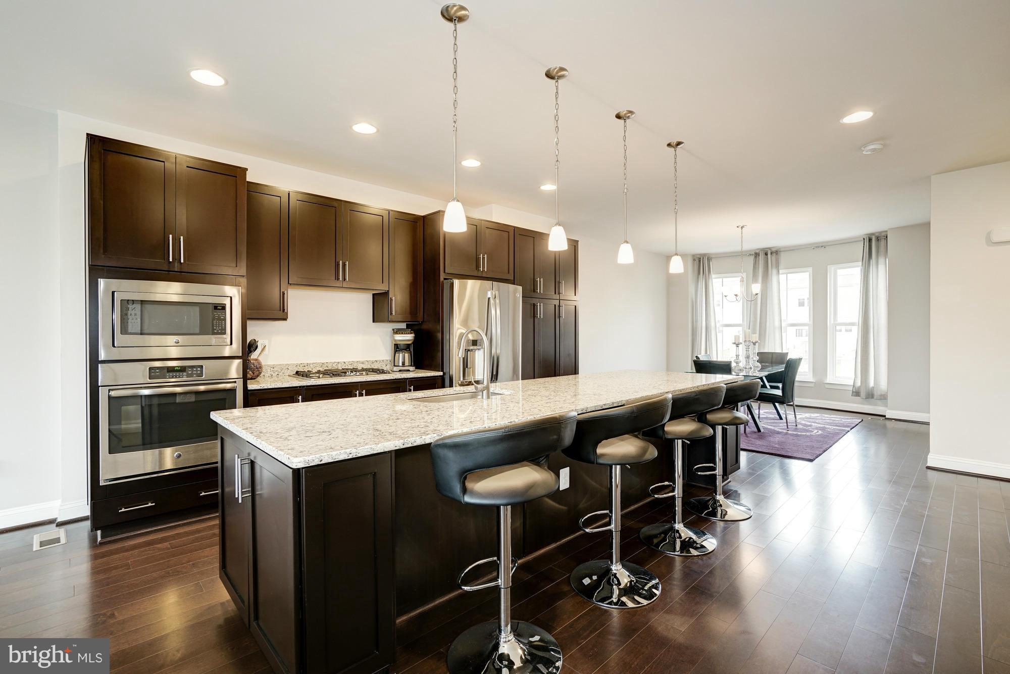 42277 Riggins Ridge Terrace Ashburn, VA 20148 - Photo 10 of 30 a kitchen with stainless steel appliances kitchen island granite countertop a table chairs sink and stove