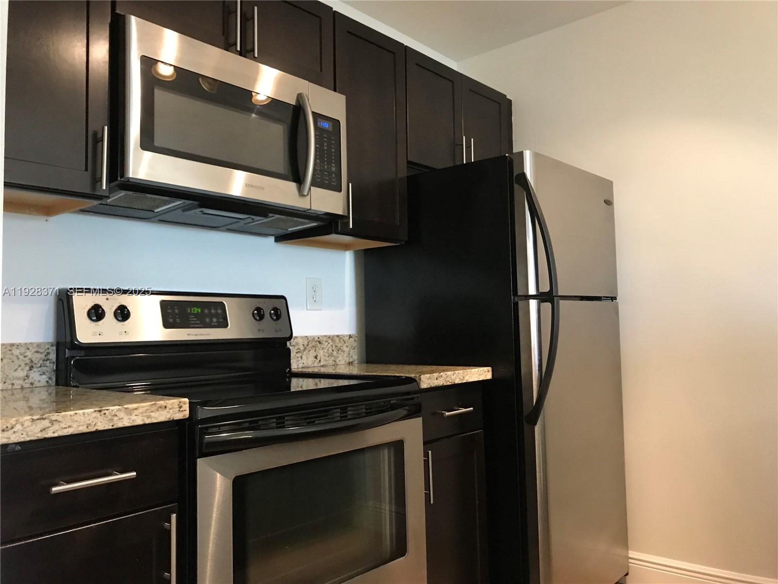 1250 Southwest 113th Terrace, Unit 101 Pembroke Pines, FL 33025 - Photo 5 of 17 a kitchen with stainless steel appliances granite countertop a stove microwave and refrigerator