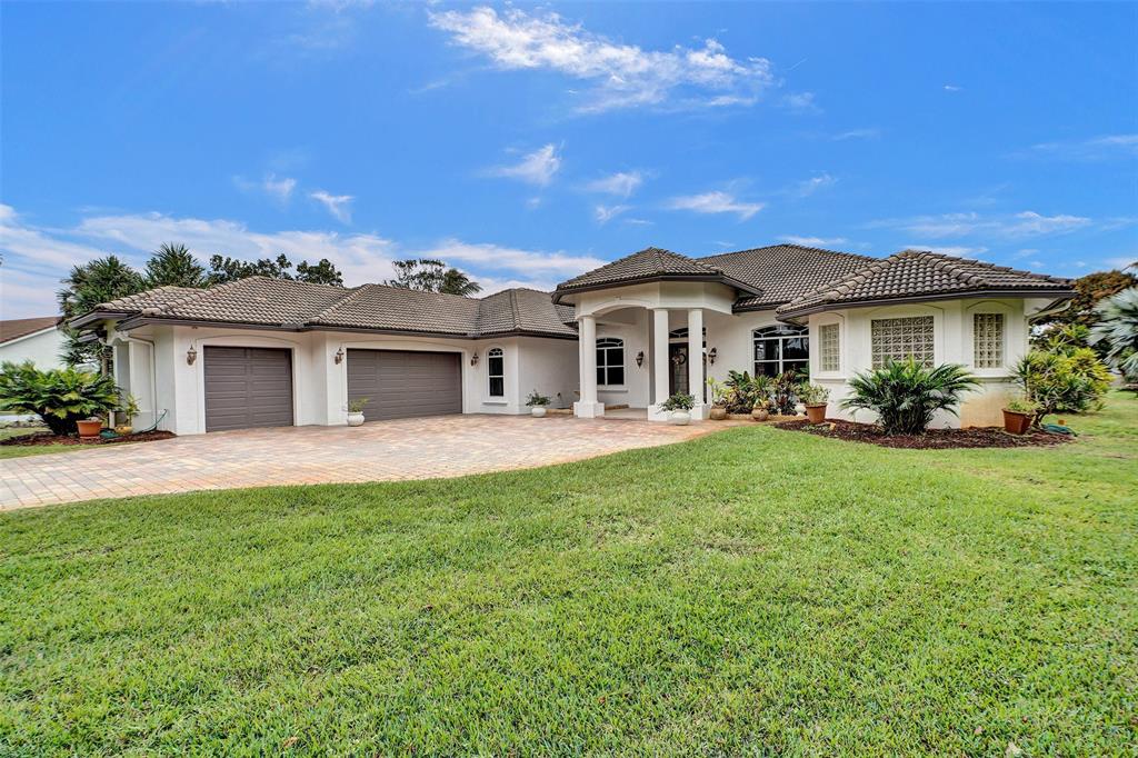 8426 Sawpine Road Delray Beach, FL 33446 - Photo 16 of 91 a front view of a house with a yard and potted plants