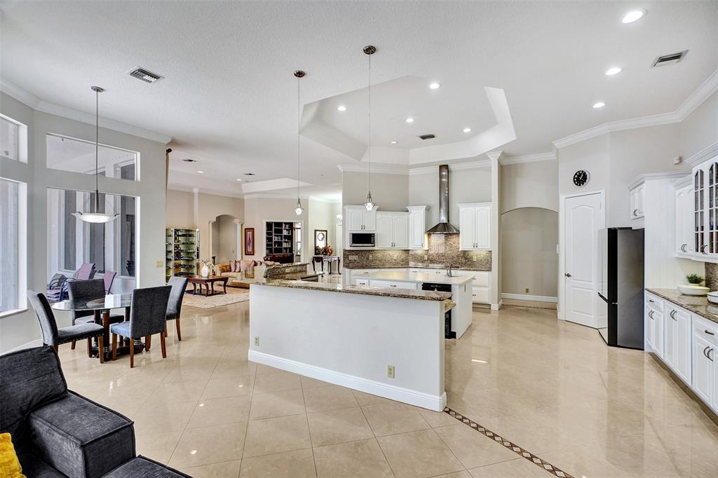 8426 Sawpine Road Delray Beach, FL 33446 - Photo 42 of 91 a kitchen with stainless steel appliances kitchen island granite countertop a table and chairs in it