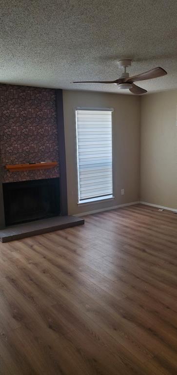 5532 Boca Raton Boulevard, Unit 290 Fort Worth, TX 76112 - Photo 11 of 16 Living space featuring wood-finish flooring, a stone-accented fireplace with a wood mantle, two windows with blinds, and a ceiling fan