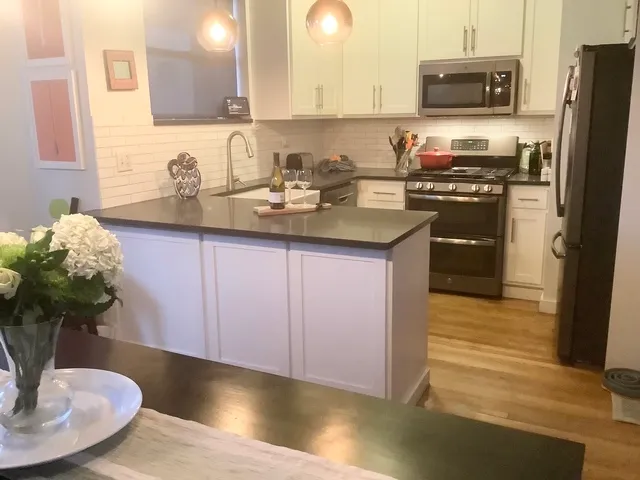 a kitchen with stainless steel appliances granite countertop a sink a stove a microwave a refrigerator and cabinets