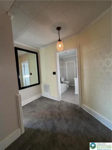 a view of a hallway with wooden floor and a bathroom