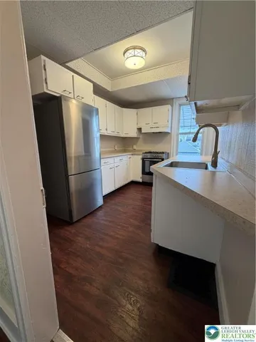 a kitchen with kitchen island a sink a stove a refrigerator and cabinets