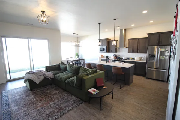 a living room with stainless steel appliances furniture a rug and a window