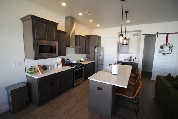 a kitchen with a refrigerator a stove a sink dishwasher with a dining table and chairs