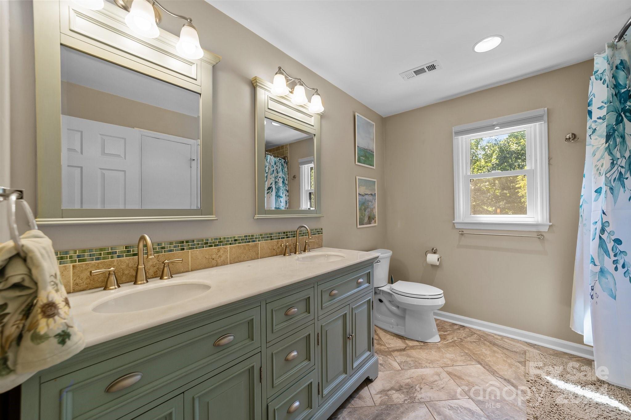 1060 Churchill Road Davidson, NC 28036 - Photo 36 of 41 a bathroom with a granite countertop double vanity sink a mirror and a toilet
