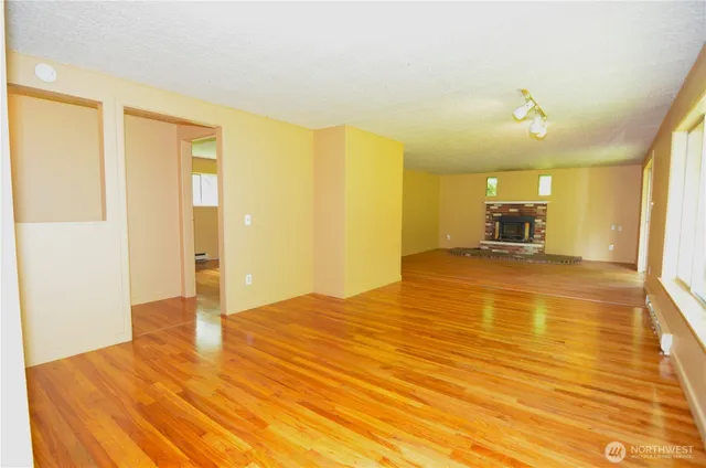 a view of an empty room with kitchen and a window