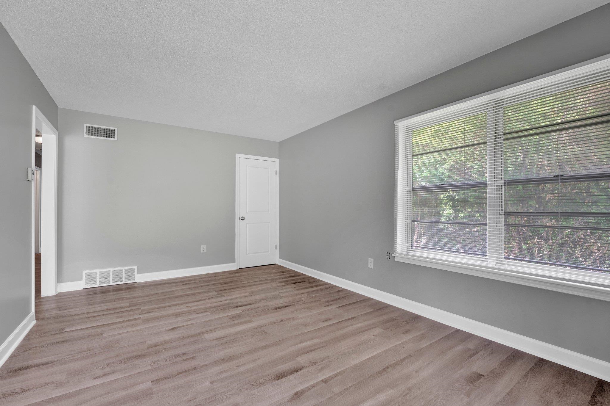 175 Stoneham Road Memphis, TN 38109 - Photo 3 of 25 a view of an empty room with wooden floor and a window