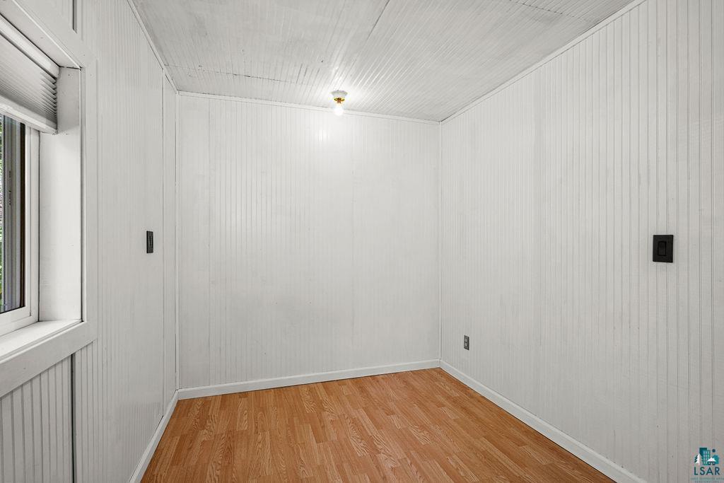 1159 Wales Road Two Harbors, MN 55616 - Photo 4 of 29 Room featuring white vertical plank walls, light wood-finish flooring, and a single-pane window