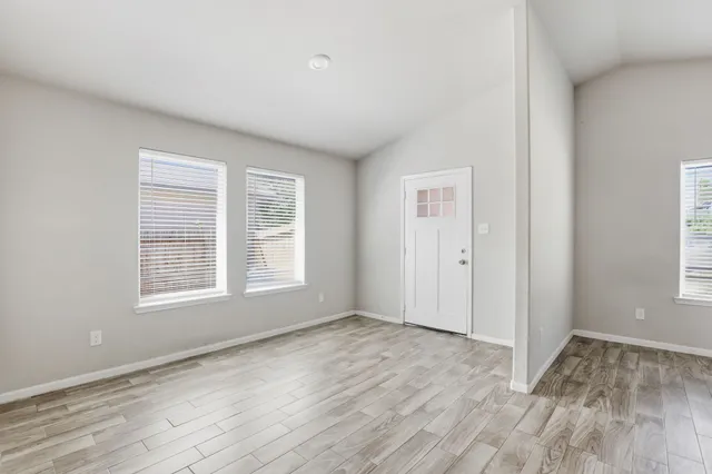 a view of an empty room with wooden floor and a window