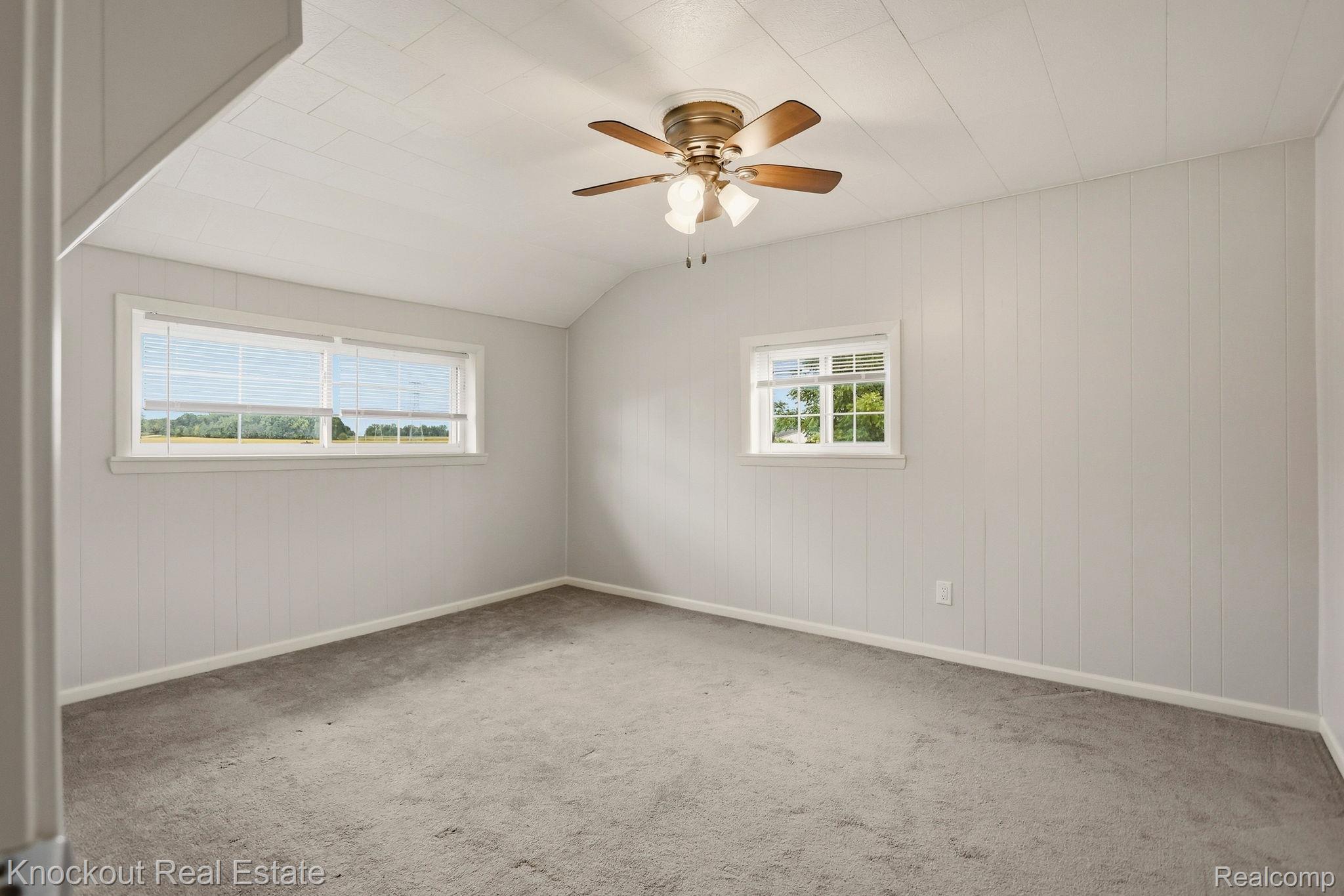 8771 Van Cleve Road Vassar, MI 48768 - Photo 21 of 44 Light gray vertical paneling, textured ceiling, two windows, and a ceiling fan with light fixture