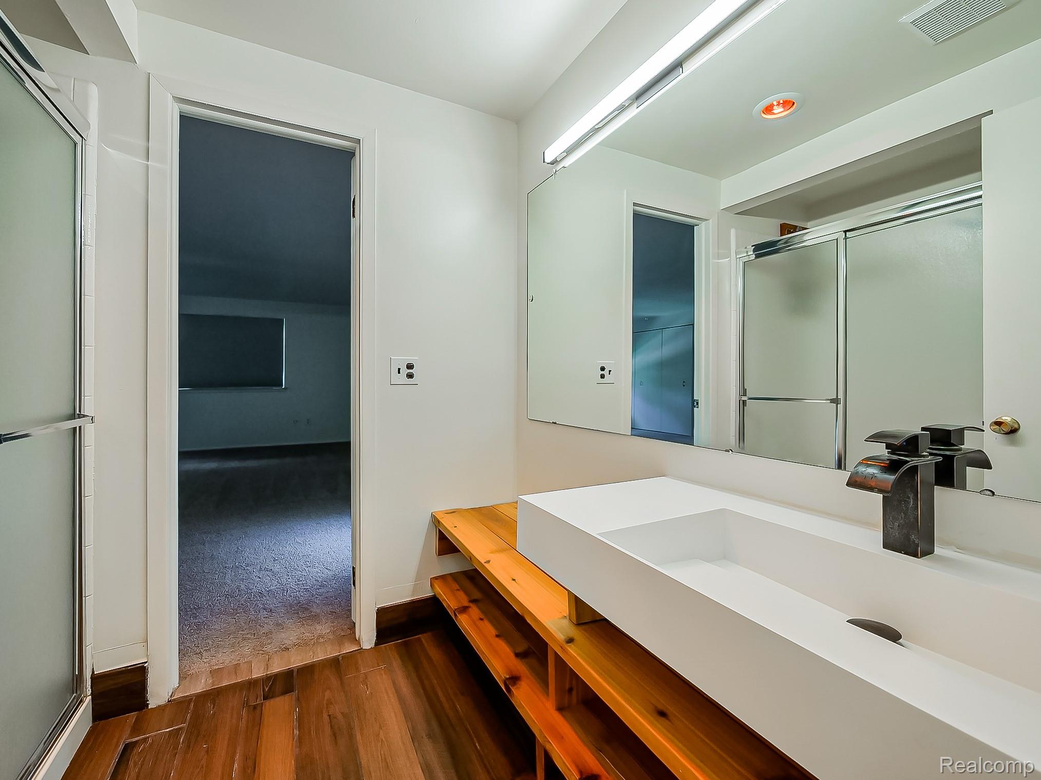 42195 Park Ridge Road Novi, MI 48375 - Photo 29 of 52 Modern floating vanity with a rectangular vessel sink, wood-finish flooring, and a mirrored medicine cabinet
